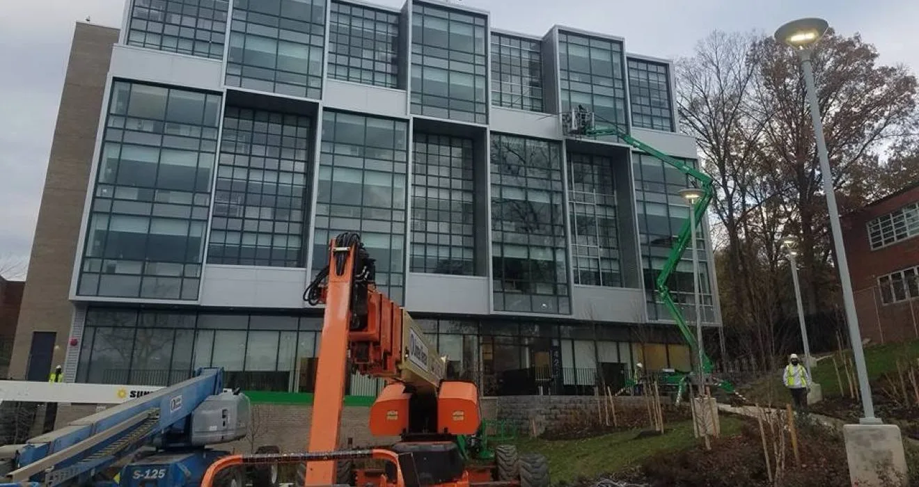 Acercamiento a una fachada de vidrio en instalación, con lifts trabajando en los pisos altos