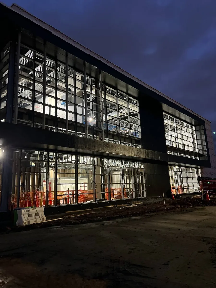 Fachada curtain wall de un edificio comercial iluminada de noche, durante la instalación